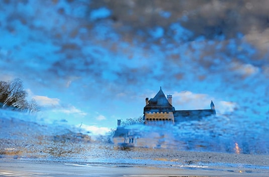 Paysage avec une maison vue à travers l’eau évoquant les perceptions et émotions en mouvement dans la relation de couple